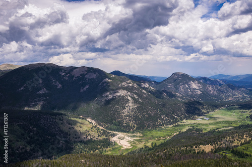 Snowy clouds over a green valley in the Rocky Mountains