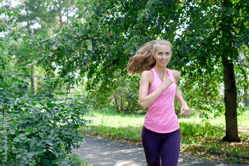 Woman runner running through the spring park road. Workout in a Park. Beautiful fit Girl. Fitness model outdoors. Woman runner running through the spring park road. Workout in a Park. Beautiful fit Girl. Fitness model outdoors.