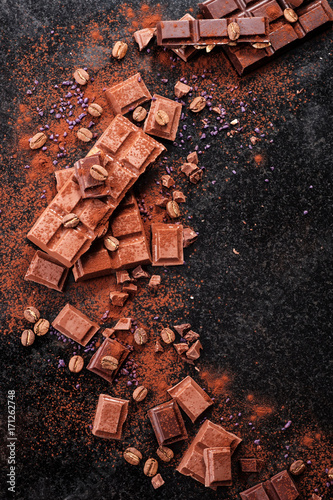 Broken chocolate pieces and cocoa powder on marble.