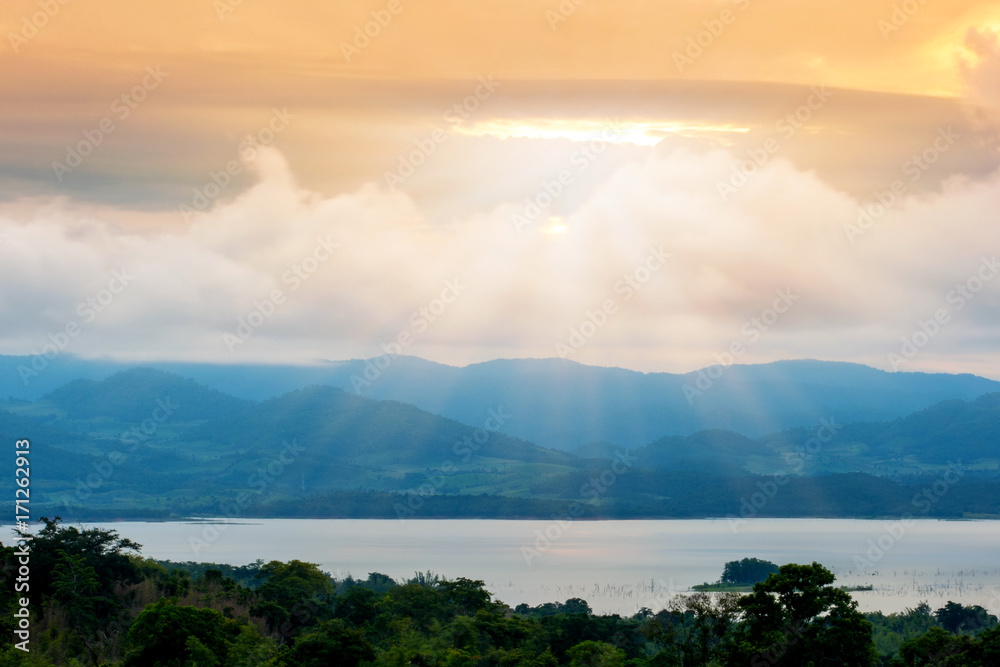 The beautiful landscape of nature in the morning with the sun light passing through the clouds to the mountains above the Si Nakharin Dam. Kanchanaburi, Thailand