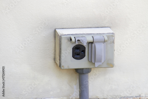 The old electrical plug next to the cream wall.
