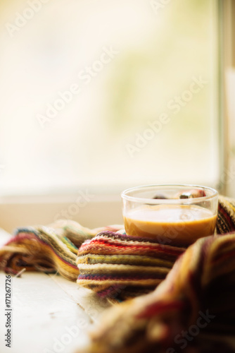 cozy soft gray blanket with a big red cup on the background of a window decorated with frost / warming moments winter holidays