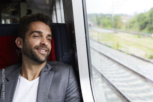 Guy relaxing in seat on train journey, smiling © sanneberg