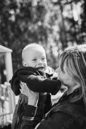 Portrait of mother who hug her joyful baby boy. Outdoors healthy child activity, active lifestyle and having fun on family summer vacation with son at the playground.