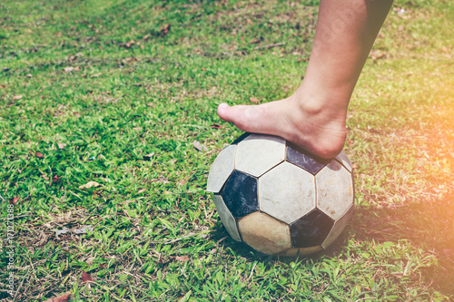 Barefoot football player tread on the soccer ball. Healthy lifestyle concept.