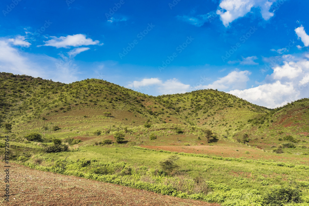Landscape View of mountains and green fields with blue sky