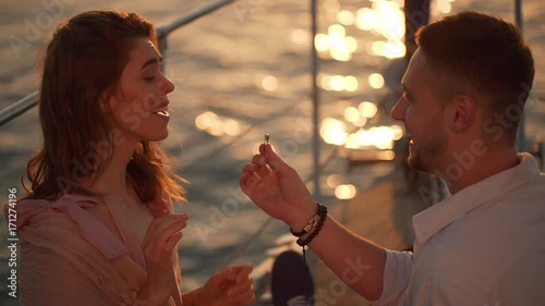 Happy young lady expressing surprise after receiving proposal to marriage and wearing engagement ring while yachting by sea in slow motion 