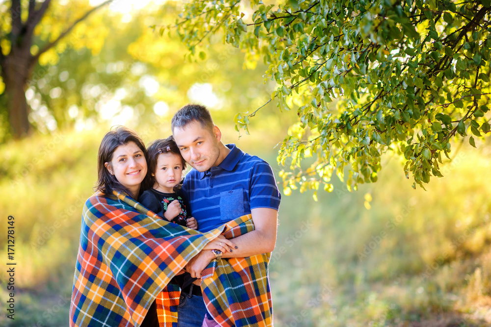happy family walking in an autumn park at sunset, hiding in a padded hug and smiling happy family walking in an autumn park at sunset, hiding in a padded hug and smiling