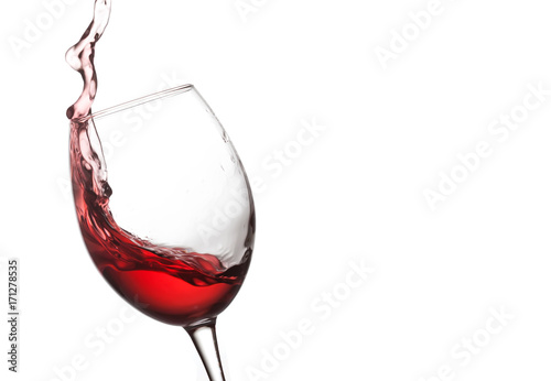 Red wine splashing. Pouring wine into crystal glass, close-up, white background. copy space.