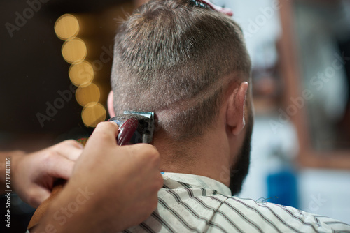 Cropped close up of a man getting his hair styled by a professional barber at the barbershop.