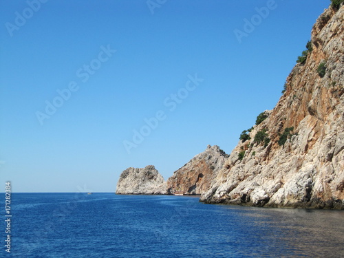 The blue sea with beautiful brown rocks with the ruins of an old fortress. Turkey, Alanya