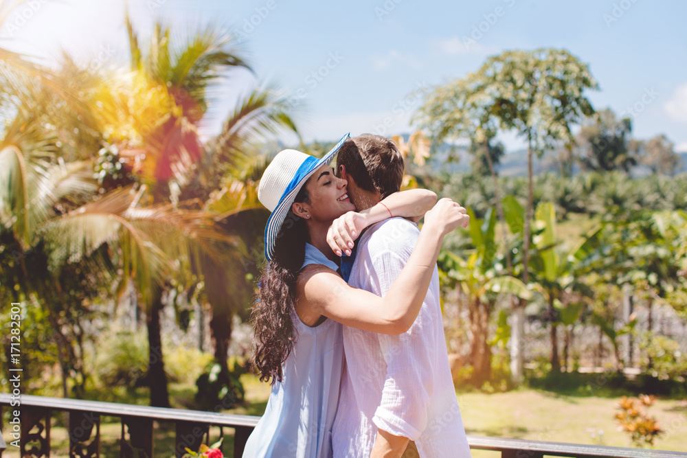 Naklejka premium Happy Man And Woman Hugging On Terrace Or Balcony With Beautiful Tropical Landscape Young Couple Embrace Outdoors