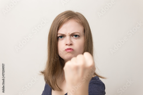 Young caucasian woman with a clearly irritated, annoyed look, show fist