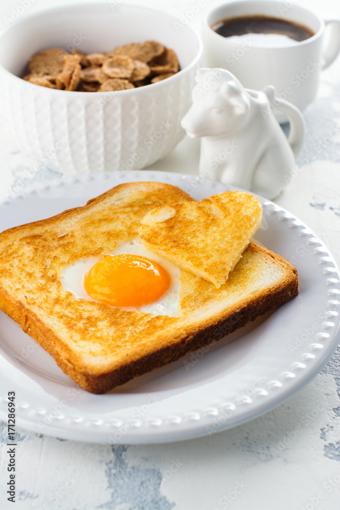 Breakfast for Valentines day: toast with heart shaped egg, muesli and coffee on white concrete table. Space for text Breakfast for Valentines day: toast with heart shaped egg, muesli and coffee on white concrete table. Space for text