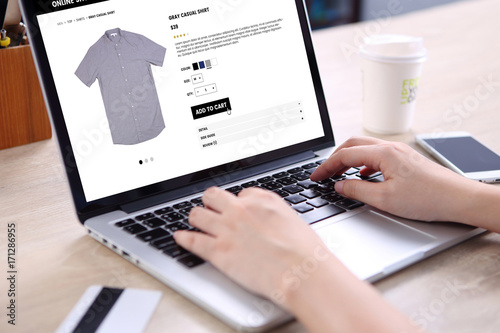 People buying casual shirt on ecommerce website with smart phone, credit card and coffee on wooden desk