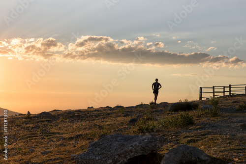 Man running on a mountain in summer during a nice sunset.