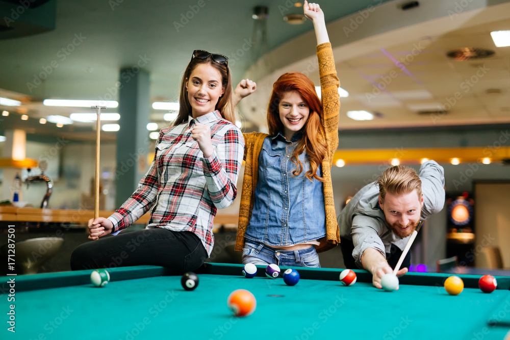 Fototapeta premium Happy friends enjoying playing pool