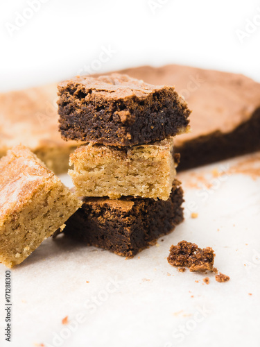 Stack of freshly baked brownies and snickerdoodle blondies squares on white baking parchment paper