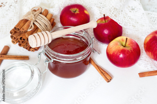 honey spoon, jar of honey, apples and cinnamon on a wooden background in a rustic style (toning) © Albina