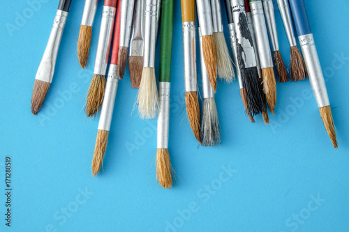 Row of artist paint brushes close up on blue  background