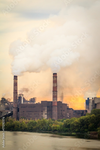 Old plant with smokestacks blowing smoke into the atmosphere