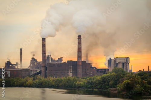 Old plant with smokestacks blowing smoke into the atmosphere
