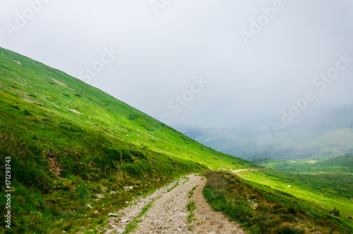 Landscape, travel, tourism. Road with pebbles going to the mountains. Horizontal frame