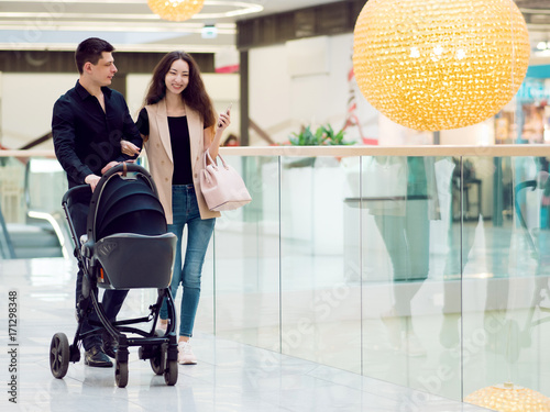 A young family, man and woman with stroller walk through the Mall