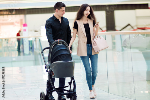 A young family, man and woman with stroller walk through the Mall