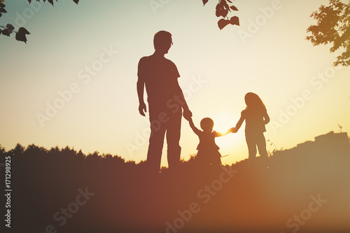 father with two daughters walk in sunset nature