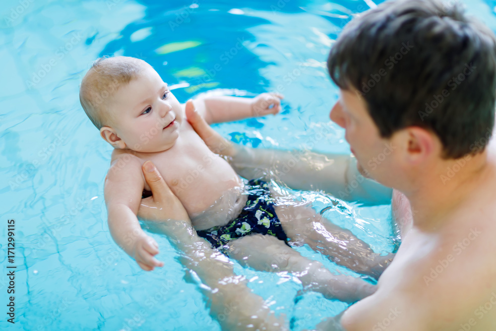 Happy middle-aged father swimming with cute adorable baby in swimming pool. Happy middle-aged father swimming with cute adorable baby in swimming pool.