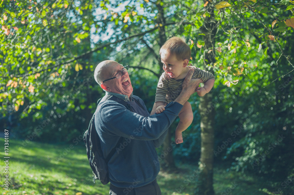 Senior man lifting baby grandson in nature Senior man lifting baby grandson in nature