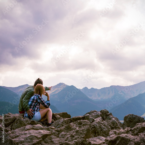 A guy and a girl are hugging on top of a mountain