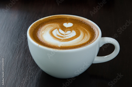 Cup of coffee with beautiful Latte art on black background.