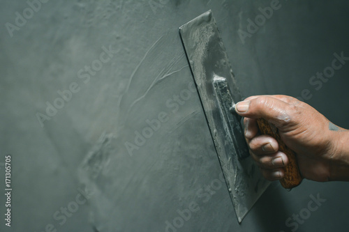 Hand of man working plastering on wall photo
