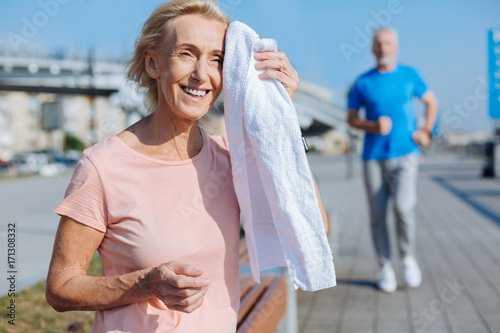 Happy woman wiping sweat from forehead with towel