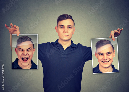 Foto Serious man holding two different face emotion masks of himself