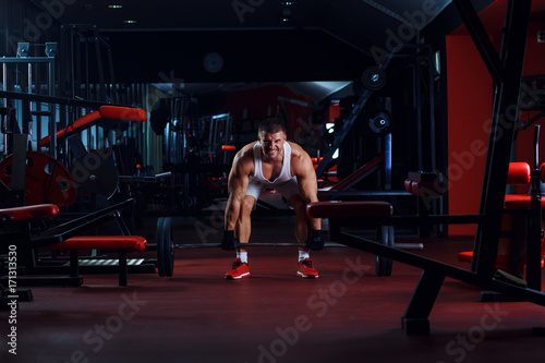 Young man exercising with weight in the gym.