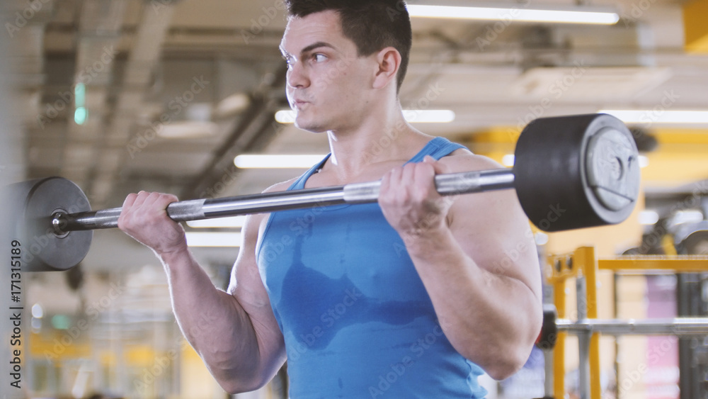 Bodybuilding in the gym - muscular man perform exercises with barbell biceps, close up Bodybuilding in the gym - muscular man perform exercises with barbell biceps, close up