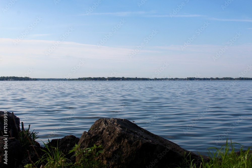 The view of the lake over a rock on the lake shore.