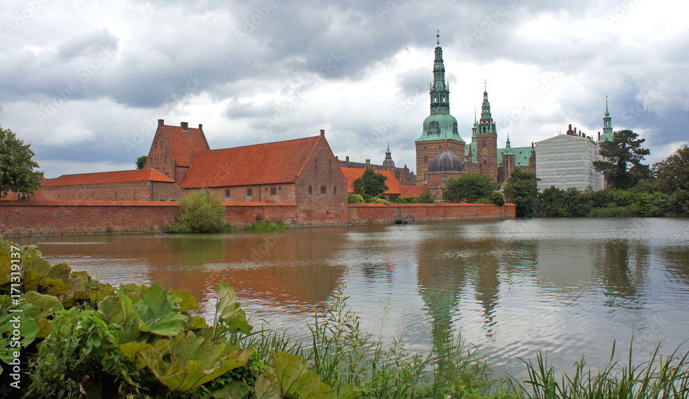 View of Frederiksborg castle (slot), Renaissance architecture, reflection of the palace in water, cloudy weather, Hillerod, Denmark View of Frederiksborg castle (slot), Renaissance architecture, reflection of the palace in water, cloudy weather, Hillerod, Denmark