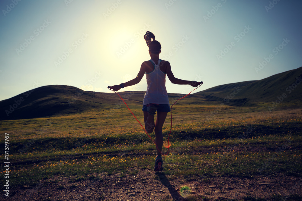 Young woman skipping rope on grassland trail