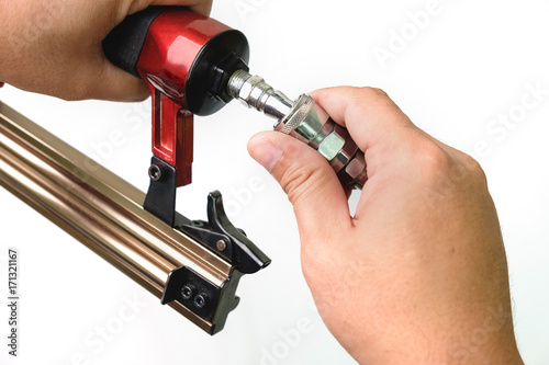 Close up a man connecting a pneumatic plug to nailer gun on white background.