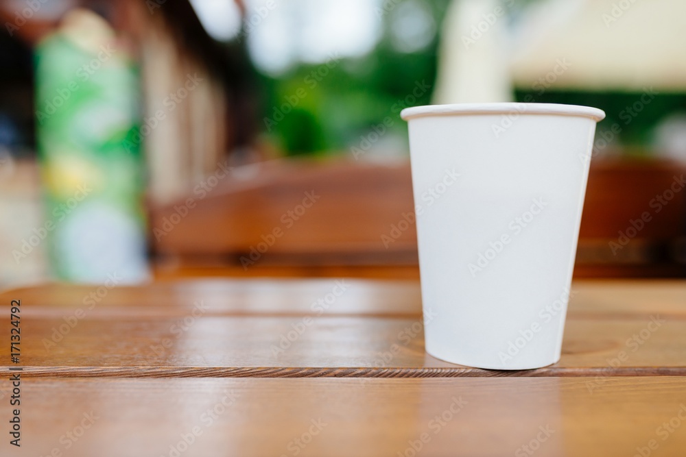 White paper coffee cup on wooden table outdoors. White paper coffee cup on wooden table outdoors.