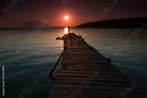 Landscape of wooden bridge in the port between sunsets © yudhistirama
