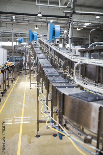 Industrial factory indoors and machinery. Robotic factory line for processing and bottling of pure spring water into canisters and bottles