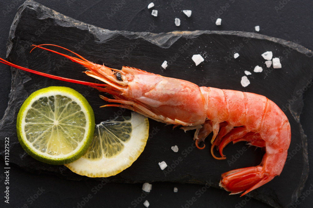 Shrimp with salt and lemon on black background