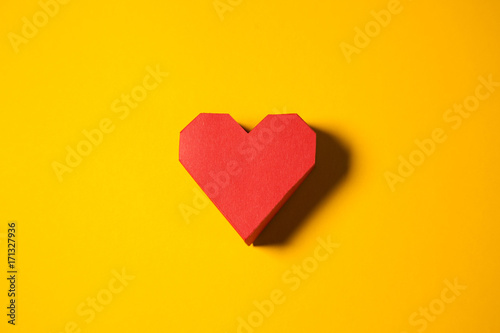 Red paper heart on a yellow background