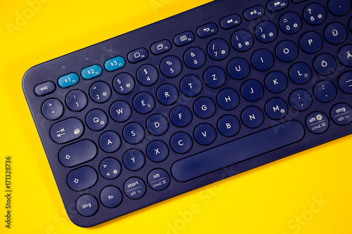 Blue wireless computer keyboard on a yellow background