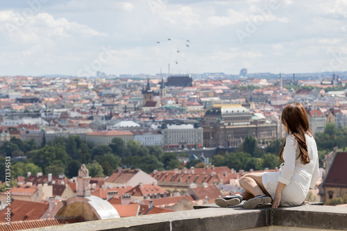 Prague, Czech Republic - August 19, 2017: Asian girl are sitting on a wall of a balcony with panoramic city views